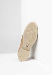 Beige Leder Schuh mit einer flachen, strukturierten, beigen Gummisohle mit runden Griffen. Zeigt das Markenlogo, das in die Sohle eingeprägt ist. Größe 37.
