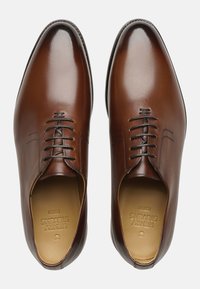 Chaussures habillées en cuir marron avec une finition brillante, dotées d'un bout arrondi, d'un laçage à six œillets et de détails de couture subtils sur les côtés.