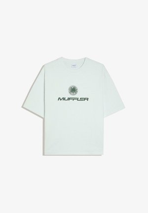 Fehér rövid ujjú póló zöld "MUFFLER" felirattal és kör alakú pálmafa logóval a mellkas közepén felül.