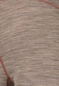 Lichtbruin textuurstof met subtiele variaties; heeft contrasterende rode stiksels langs de naad voor extra detail.