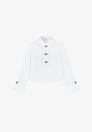 Blouse blanche courte avec un col. Dispose d'une fermeture à boutons et de manches évasées avec des boutons contrastants aux poignets. Texture douce.