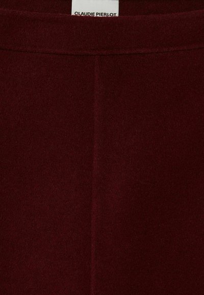 Tejido de lana burdeos con una textura suave, que presenta costuras limpias y un brillo sutil. Incluye una etiqueta rectangular de marca en la parte superior.