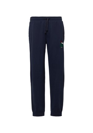 Donkerblauwe joggingbroek van zacht materiaal, met een elastische tailleband met trekkoord en elastische boorden. Voorzien van een kleine geborduurde karakterdetail.