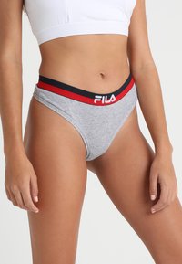 Grå bomullstanga med en kontrasterende rød og marineblå midjebånd som har merkevarenavnet "FILA" i hvite bokstaver. Glatt tekstur, minimalistisk design.