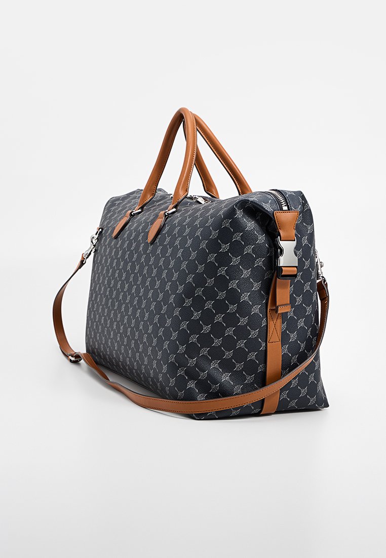 Schwarze, gemusterte Reisetasche mit schlankem Design, ausgestattet mit braunen Kunstledergriffen, abnehmbarem Schultergurt und silbernen Hardware-Details.