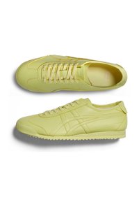 Keltaiset urheilukengät, joissa on sileä nahkapinta, nauhakiristys, teksturoitu kumipohja ja matala profiili, jossa on sivuraitteet.