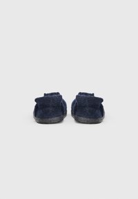 Pantofole in feltro blu navy con un design a trama, risvolto e suola in gomma. La vista laterale mette in risalto il materiale morbido e la forma.