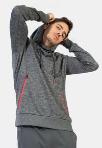 Felpa con cappuccio grigia in maglia con una finitura testurizzata, dotata di cappuccio con cordino, accenti neri e tasche laterali con zip rossa.