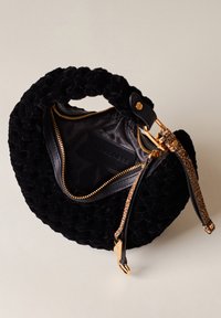 Black fabric handbag with a woven texture, gold hardware, and a leather strap. Zippered interior reveals a smooth lining and logo detail.