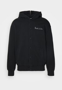 Svart hettegenser laget av mykt stoff, med en frontlukking med trykknapper og sidelommer. Brodert "Dark Side" tekst på brystet.