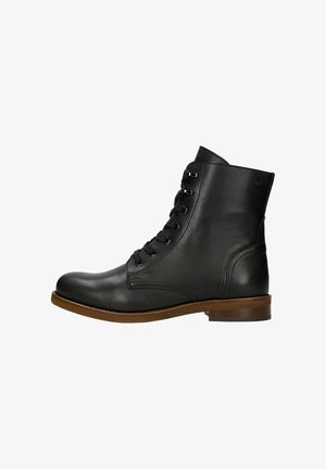 Bottine en cuir noir avec un bout arrondi, fermeture lacée à l'avant, œillets en métal et semelle brune contrastante. Texture lisse et accents minimaux.