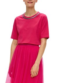 Fuchsia t-shirt met korte mouwen en een ronde hals, versierd met zilveren embellishments. Draagt met een bijpassende fuchsia tule rok, met een vloeiende textuur.