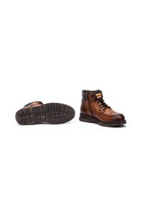 Bottines en cuir marron avec des accents noirs, design à lacets, col rembourré, semelle en caoutchouc texturée, fermeture éclair sur le côté et détails de couture contrastants.