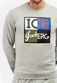 Grauer Sweatshirt mit langen Ärmeln, das ein farbenfrohes quadratisches Grafikdesign zeigt, das den Text "ICE" und "Iceberg" in unterschiedlichen Schriftarten und Farben enthält.
