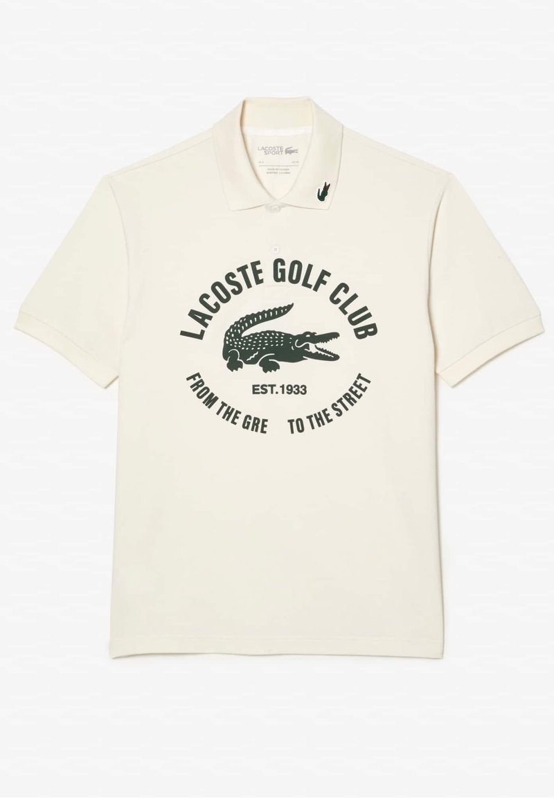 Polo crème arborant un logo vert du Lacoste Golf Club, un graphisme de crocodile et du texte. Le matériau semble lisse avec un design de col classique.