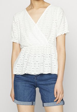 Haut blanc à manches courtes avec un design croisé, en tissu texturé et taille peplum. Associé à un short en jean bleu, ourlé au bas.