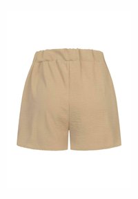 Beige šortky s elastickým pasem, měkkou texturou a volným střihem. Zadní strana má hladký, nezdobený povrch bez kapes.