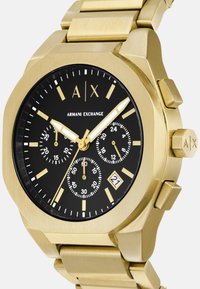 Kuldtoonitud roostevabast terasest kell musta dial'iga, kolme aladiagrammiga, kuupäevanäidikuga ja julgete tunni märkidega. Omab massiivset kaheksanurkset korpust.