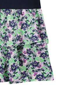 Spódnica w kwiaty z warstwowym wzorem i granatowym paskiem w talii. Wzór zawiera fioletowe i niebieskie kwiaty na jasnorozowym tle w bieli.