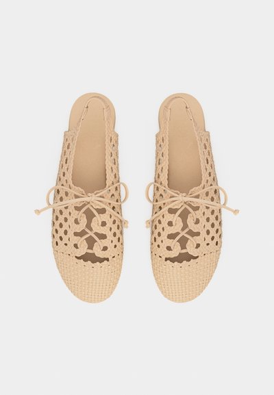Μπεζ υφαντά παπούτσια τύπου slip-on με ανοιχτό σχεδιασμό πλέγματος και διακοσμητικούς φιόγκους πάνω, επίπεδη σόλα και λουράκια τύπου slingback.