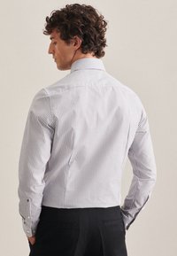 Gestreiftes Hemd in Weiß und Marineblau, mit langem Ärmel, taillierter Silhouette und knöpfbaren Manschetten mit einer glatten Textur.