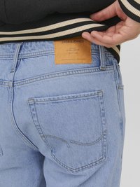 Jean en denim bleu clair avec une coupe droite, comportant une patch en cuir étiqueté "JACK & JONES" et des détails de couture subtils sur les poches.