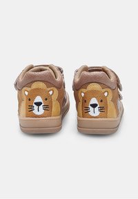Scarpe per bambini marroni con ricamo di una faccia di leone sul tallone, dotate di chiusure in velcro e un design testurizzato.