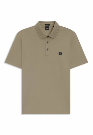 Beige pikétröja i bomull med en klassisk krage, tre svarta knappar och en cirkulär logotyp på vänster bröst. Korta ärmar.