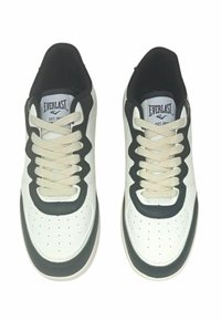 Sneaker atletiche bianche con accenti neri, in pelle texturizzata e suola chunky. Design con lacci beige e dettagli perforati.