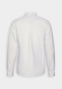 Camisa blanca de manga larga con cuello botón, costura en el yugo trasero, puños de botón simples y un diseño minimalista. Textura de tela de algodón.