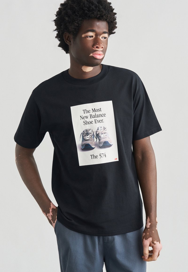 Μαύρο βαμβακερό t-shirt με γραφικό απεικόνισης αθλητικών παπουτσιών και κείμενο «Το πιο νέο παπούτσι New Balance ποτέ» σε λευκό, με στρογγυλή λαιμόκοψη και κοντά μανίκια.