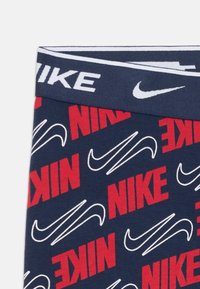 Slip sportivo blu navy con un design a motivi che presenta il testo rosso "NIKE" e loghi swoosh bianchi, fascia elastica con brand "NIKE".