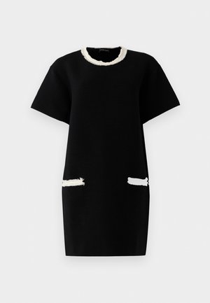 Black short-sleeve dress with textured fabric, white fringed neckline, and white fringed accents on front pockets.