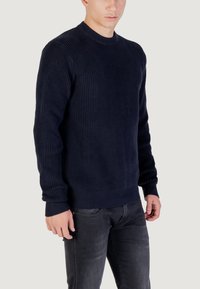 Maglione a coste di colore blu navy con scollo rotondo. Presenta un tessuto testurizzato, maniche lunghe e un bordo aderente ai polsi e all'orlo.
