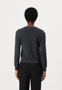 Maglione di lana grigio scuro con maniche lunghe, polsini e orlo a coste, e un semplice design a girocollo. Nessun motivo visibile o dettagli in metallo.