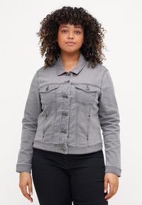 Chaqueta de mezclilla gris con dos bolsillos en el pecho, cierre de botones y mangas largas. Presenta un cuello clásico y detalles de costura visibles.