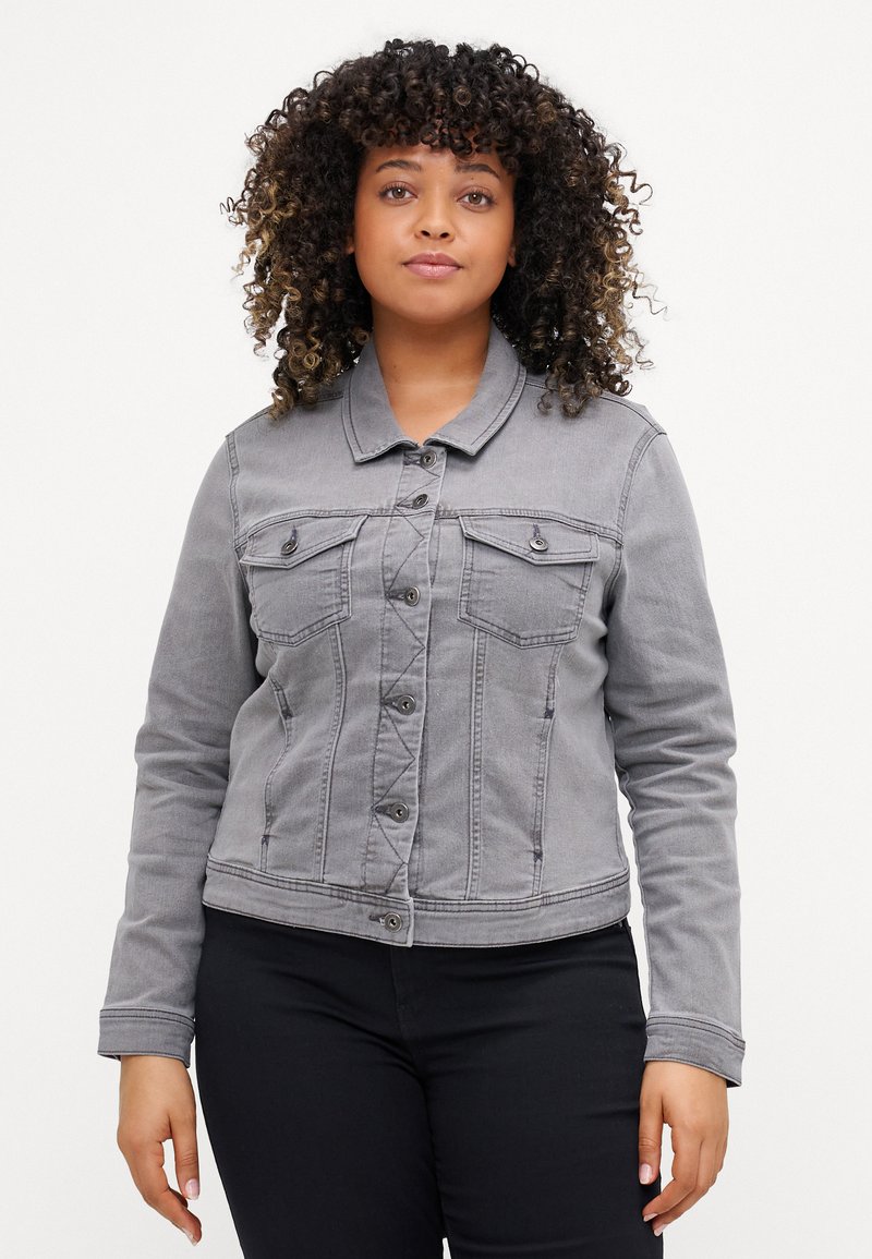 Chaqueta de mezclilla gris con dos bolsillos en el pecho, cierre de botones y mangas largas. Presenta un cuello clásico y detalles de costura visibles.