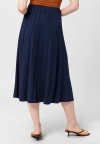 Gonna blu navy, lunga fino al ginocchio, con una vita elastica e un tessuto morbido e fluente. Texture liscia con un design semplice e senza decorazioni.