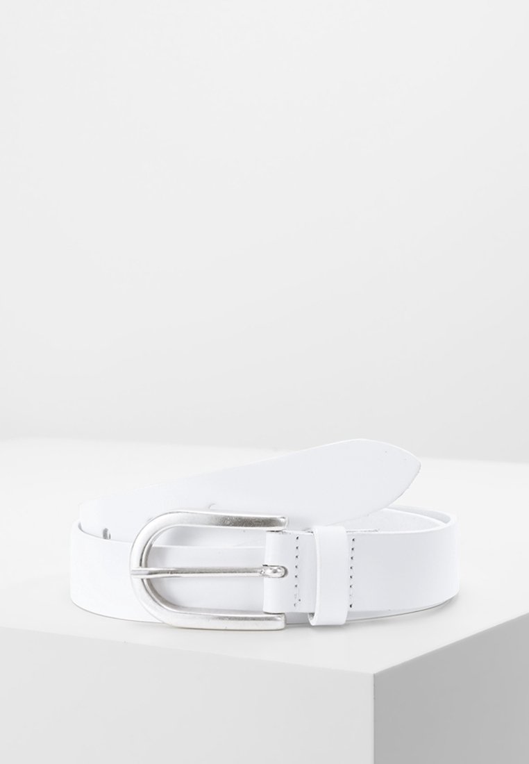 Ceinture en cuir blanc avec boucle incurvée en métal argenté, enroulée et posée sur une surface blanche sur fond clair uni.