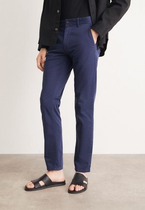 Chinos en coton bleu marine avec une coupe slim, dotés de poches latérales et d'une fermeture à bouton, associés à des sandales à glissière texturées noires.
