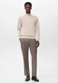 Light beige, long-sleeve pullover with a quarter-zip neckline. Paired with gray tailored trousers featuring side pockets and a slim fit. Black shoes.