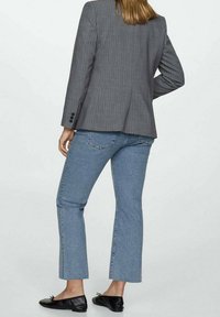 Blazer gris con rayas finas combinado con jeans cortos de color azul claro. Zapatos planos negros, costuras visibles y sutil textura en la tela.