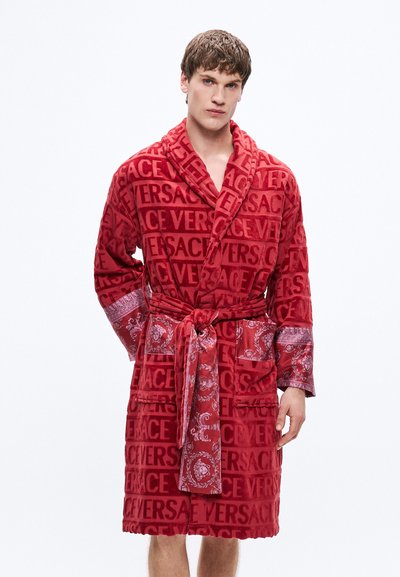 Roter Plüschbademantel mit einem durchgehenden Versace-Logo-Muster, gemusterten Ärmeln und Taschen, in der Taille mit einem passenden Gürtel gebunden.
