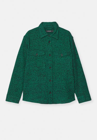 Chemise verte à motifs, avec deux poches sur la poitrine, fermeture à boutons à l'avant et manches longues. Fabriquée dans un matériau texturé avec un design moucheté.