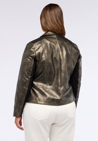 Giacca di pelle verde oliva metallizzata con vestibilità su misura, cuciture dettagliate e accenti in tessuto nero sulle maniche. Texture liscia, polsini con zip.
