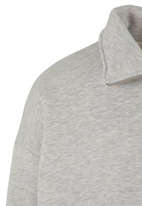 Sudadera gris con cuello alto y cremallera hasta media altura. Confeccionada en un tejido suave y texturizado. Presenta un collar tipo stand y una cremallera parcial en el frente para un ajuste ajustable.