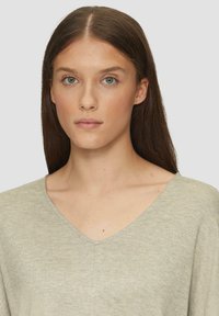Hellgrauer V-Ausschnitt-Pullover mit weicher Textur und lockerer Passform, mit geradem Saum und minimalen Nähdetails.