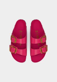 Ζευγάρι από φωτεινά ροζ σανδάλια Birkenstock με δύο ιμάντες με χρυσά αγκράφες, μέγεθος 39, απεικονιζόμενα από πάνω σε λευκό φόντο.