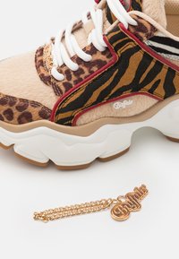 Les baskets Buffalo présentent un mélange de fourrure marron, de motifs léopard et zèbre, avec des lacets blancs et une semelle blanche épaisse. Comprend un charme en or avec logo.