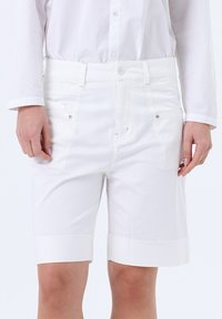 Witte katoenen shorts met een getailleerde pasvorm, voorzien van een platte voorkant, zijzakken en opgerolde cuffs. Gladde textuur en een schoon ontwerp.
